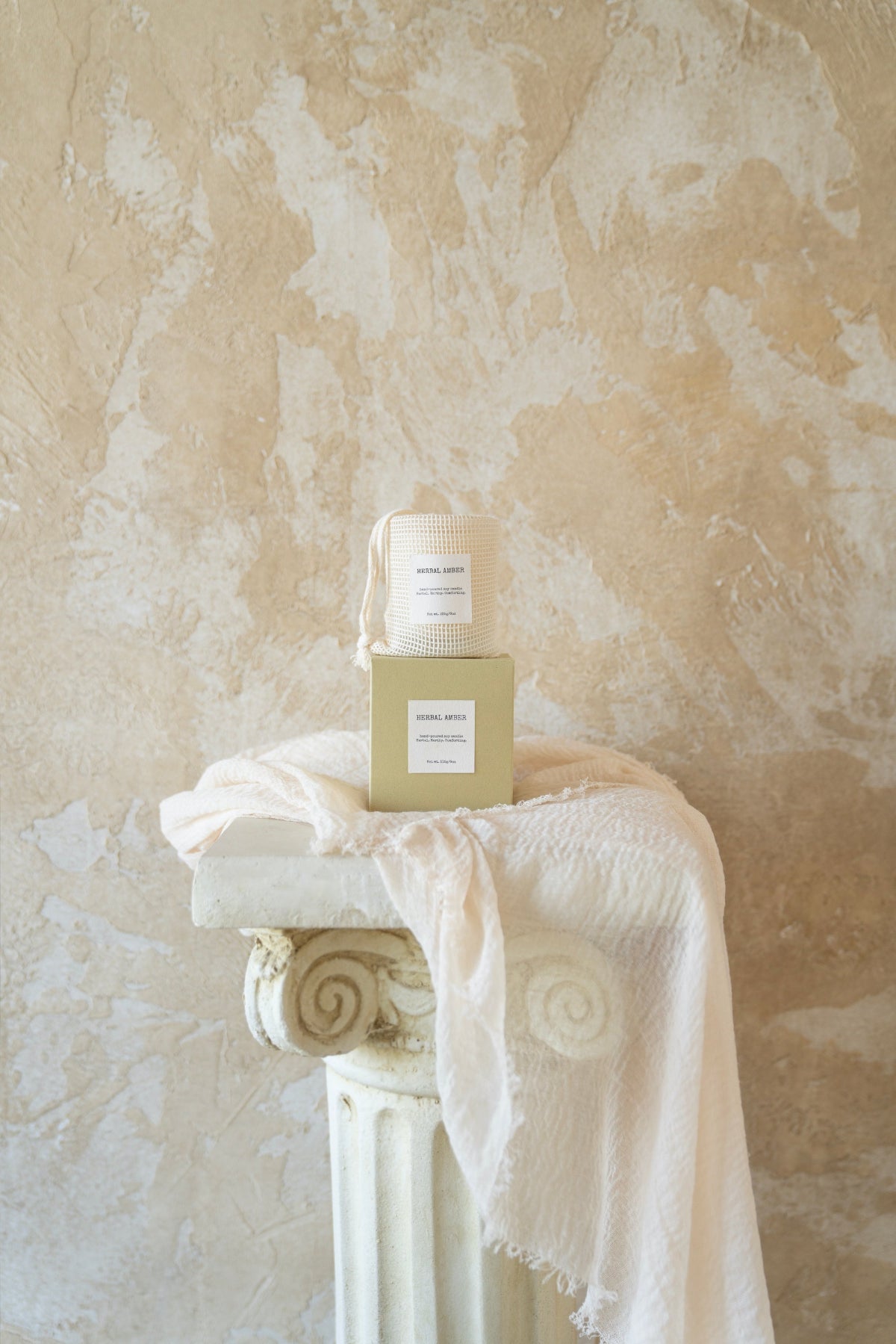 Herbal Amber candle box with matching textured pouch, styled on a soft white cloth – packaging by Enclify