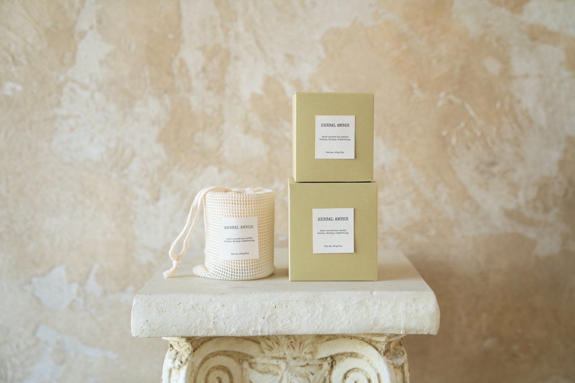 Natural-toned Herbal Amber candle boxes displayed with reusable textured pouch – eco-conscious packaging by Enclify