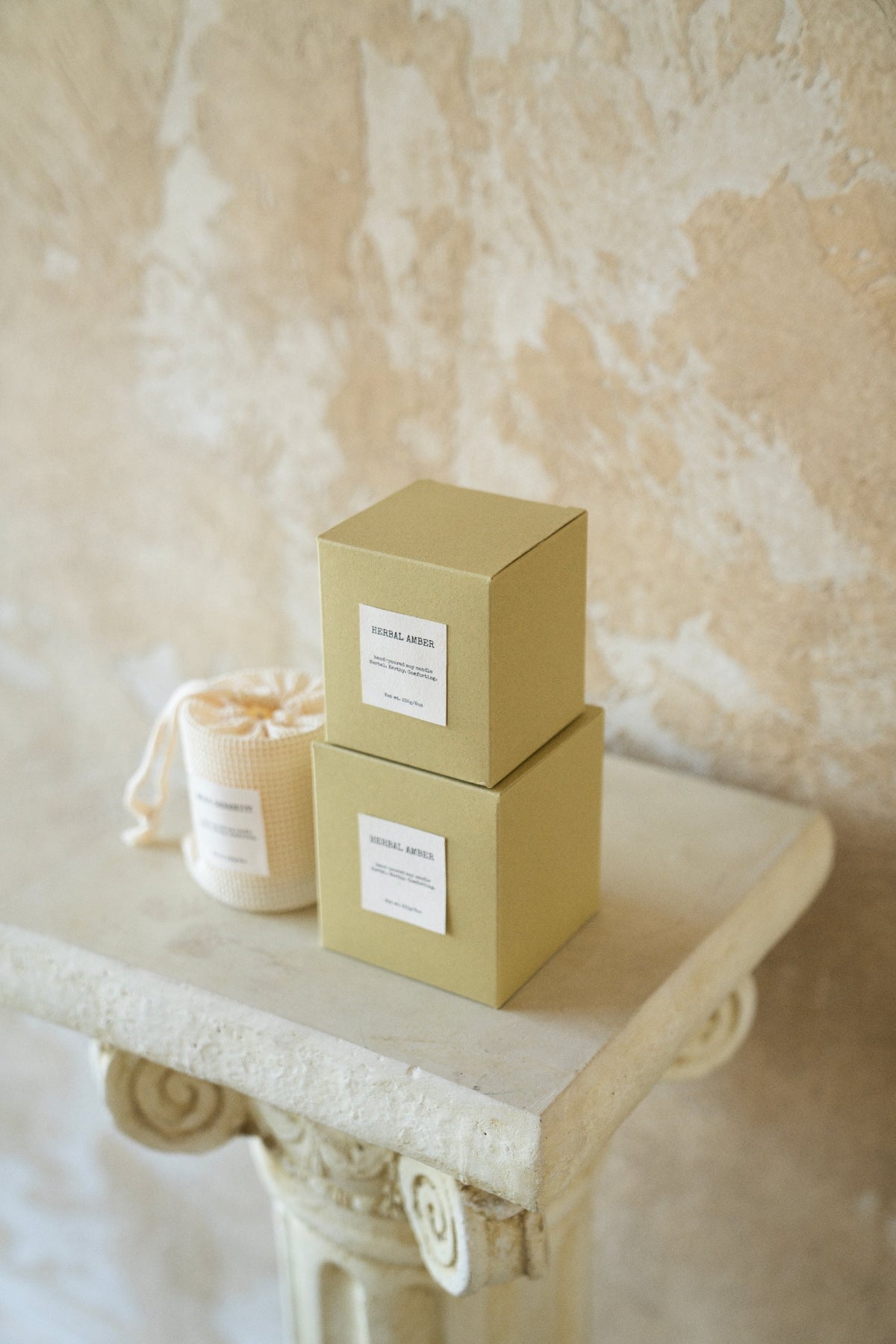 Side angle of stacked Herbal Amber candle boxes with soft pouch, highlighting minimalist design and organic texture – Enclify